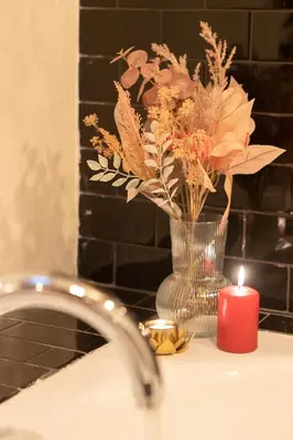 a candle and a vase with flowers on a sink at Cloe Suite - A due passi da Villa Borghese in Rome