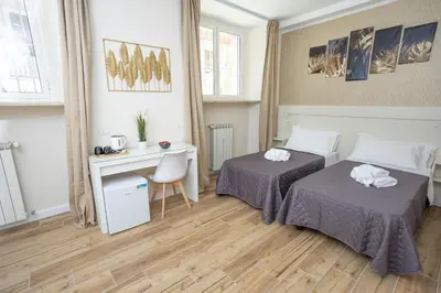 a room with two beds and a desk and a desk at Sant'Erasmo Rooms in Rome