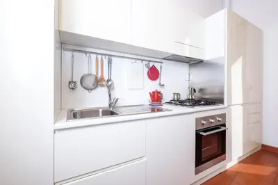 a white kitchen with a sink and a stove at Trastevere Charming Retreat on Cobblestone Street in Rome