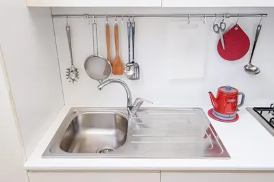 a kitchen sink with utensils hanging above it at Trastevere Charming Retreat on Cobblestone Street in Rome