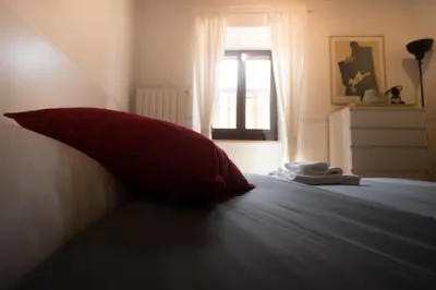 a red pillow sitting on a bed with a window at Casa Q163A Tuscolana Next to Metro in Rome