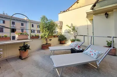 a balcony with two white chairs and potted plants at Beautiful apartment with amazing Rooftop&Jacuzzi in Rome