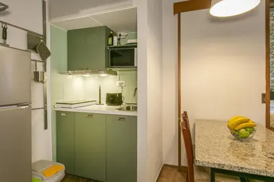 a small kitchen with green cabinets and a table at Trevi Little Palace #4 in Rome