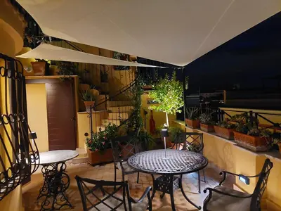 a patio with two tables and chairs and plants at Anita in Rome