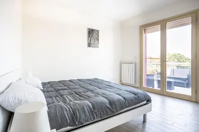 a white bedroom with a bed and a balcony at Urban Retreat -private parking+terrace in Rome