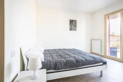 a white bedroom with a bed and a window at Urban Retreat -private parking+terrace in Rome