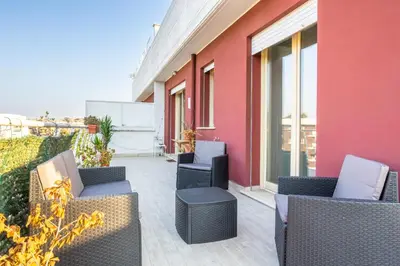 a patio with wicker chairs and a pink building at Urban Retreat -private parking+terrace in Rome