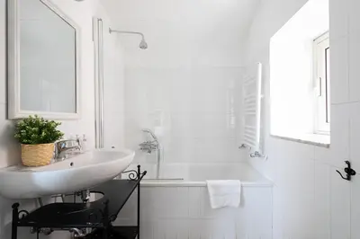 a white bathroom with a sink and a tub at Rooftop Colosseum in Rome