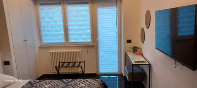 a bedroom with blue blinds on a window and a desk at Balcone sul parco in Rome