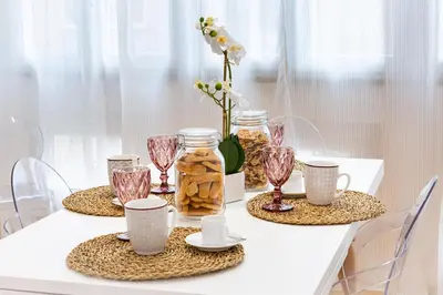 a table with two plates and glasses and flowers at Noh collection 3BDR apartment- Trastevere Area in Rome