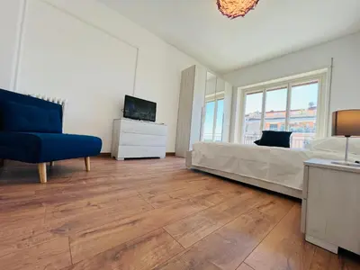 a bedroom with a bed and a tv and a blue chair at Stazione Tiburtina - Camesena Apartment in Rome