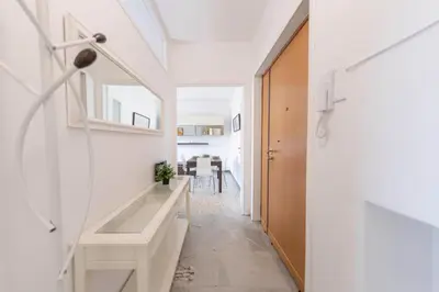 a hallway with white walls and a staircase with a mirror at [Centro Storico-5min Vaticano] Domus in Rome