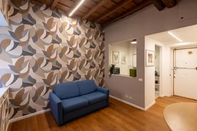 a living room with a blue chair in front of a wall at Roma Centro Storico Luxury - Via del Corso in Rome