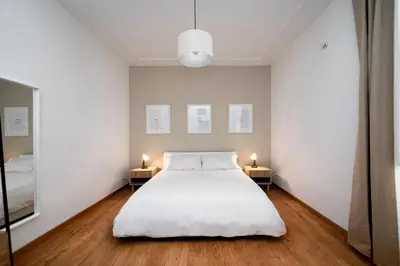 a bedroom with a white bed and two tables with lamps at VATICAN VIBES in Rome