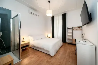 a bedroom with a white bed and a glass shower at VATICAN VIBES in Rome