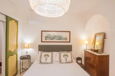 a bedroom with a bed and a mirror and a chandelier at Via Giulia Charming Atelier apartment in Rome