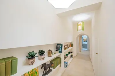a hallway with white walls and shelves with plants at Via Giulia Charming Atelier apartment in Rome