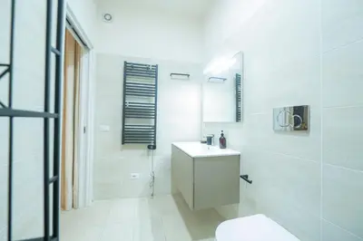 a white bathroom with a sink and a mirror at Via Giulia Charming Atelier apartment in Rome