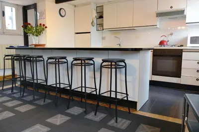 a kitchen with white cabinets and black bar stools at Appartamento Coronari in Rome