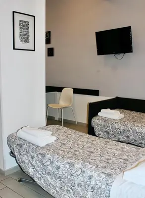 a room with two beds and a chair and a flat screen tv at St Peter's View in Rome