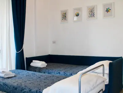 a bedroom with two beds with blue curtains and a window at St Peter's View in Rome