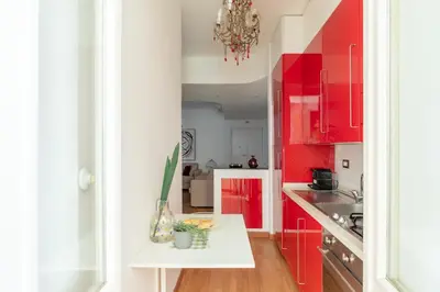 a kitchen with red cabinets and a white table at iFlat Red Roman Apartament in Rome