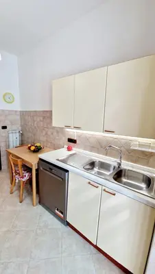 a kitchen with white cabinets and a sink and a table at Giulia Home Apartment Metro Conca D'Doro Roma in Rome