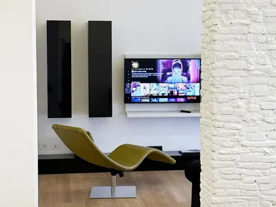 a living room with a television and a green chair at ARCAsuite Tritone Luxury in Rome