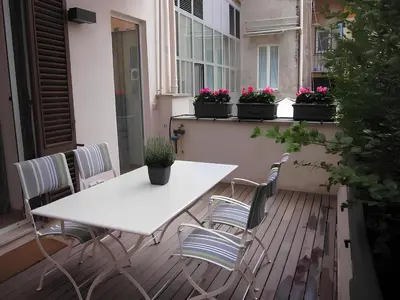 a white table and chairs on a balcony with potted plants at The Apartment at Spanish Steps in Rome