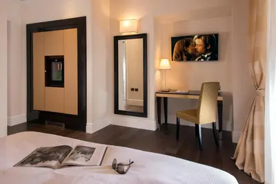 a bedroom with a bed with a desk and a mirror at Tridente Suites in Rome