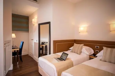 a hotel room with two beds with a laptop on it at Tridente Suites in Rome