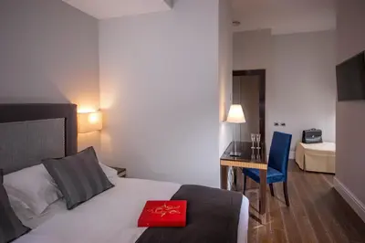 a bedroom with a bed and a desk with a red book on it at Tridente Suites in Rome