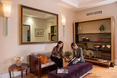 two women standing in a living room with a purple couch at Tridente Suites in Rome