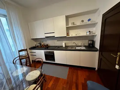a kitchen with white cabinets and a glass table at 2MG: appartamento con terrazzo nel cuore di Roma! in Rome