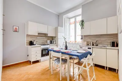 a kitchen with white cabinets and a table with chairs at Colors & Culture near Colosseum in Rome