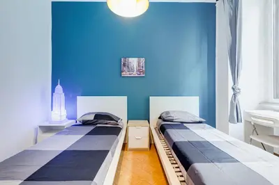 two beds in a room with a blue wall at Colors & Culture near Colosseum in Rome