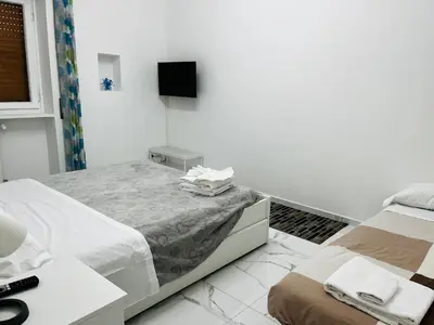 a white room with two beds and a television at Suite San Damaso in Rome