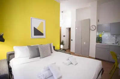 a bedroom with a white bed and a yellow wall at Monti Colosseum in Rome