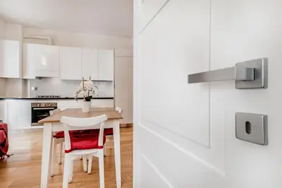 a kitchen with white cabinets and a table and chairs at BBHOME Elegant apartment at Saint Peter front of Vatican in Rome