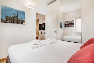 a white bedroom with two beds and a large mirror at BBHOME Elegant apartment at Saint Peter front of Vatican in Rome