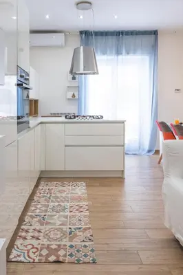 a kitchen with white cabinets and a rug on the floor at Cozy flat with terrace at Trastevere train station in Rome
