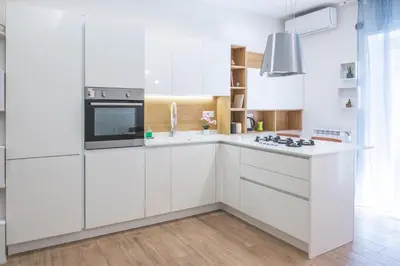 a white kitchen with white cabinets and a stove at Cozy flat with terrace at Trastevere train station in Rome