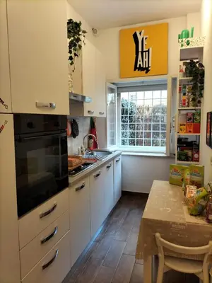 a kitchen with white cabinets and a table and a window at Trastevere Gianicolense casa con giardino in Rome