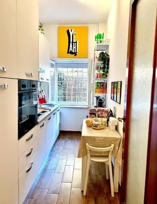 a kitchen with white cabinets and a table and a window at Trastevere Gianicolense casa con giardino in Rome