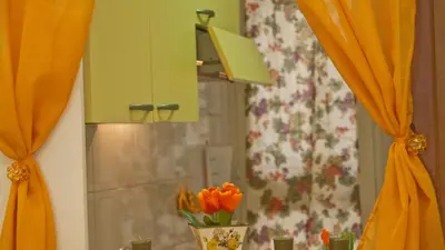 a mirror with orange curtains and a vase with orange flowers at Rental in Rome Celeste Apartment in Rome