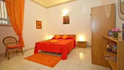 a bedroom with a bed with an orange blanket and a chair at Rental in Rome Celeste Apartment in Rome