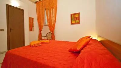 a bedroom with a red bed with orange sheets and pillows at Rental in Rome Celeste Apartment in Rome