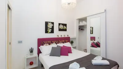 a bedroom with a large white bed with pink pillows at Consulta By Rental In Rome in Rome