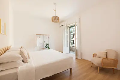 a white bedroom with a bed and a chair at [Ampio appartamento vicino al Vaticano] in Rome