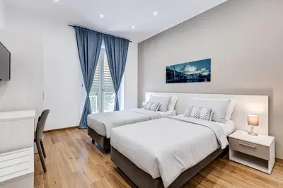 a bedroom with two beds and a desk and a tv at San Pietro Vatican Apartments in Rome